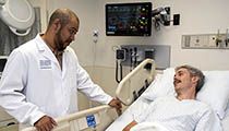 Doctor standing with a bed-ridden patient in a hospital room