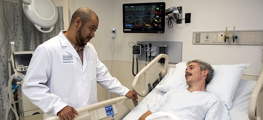 Doctor standing with a patient in a hospital bed